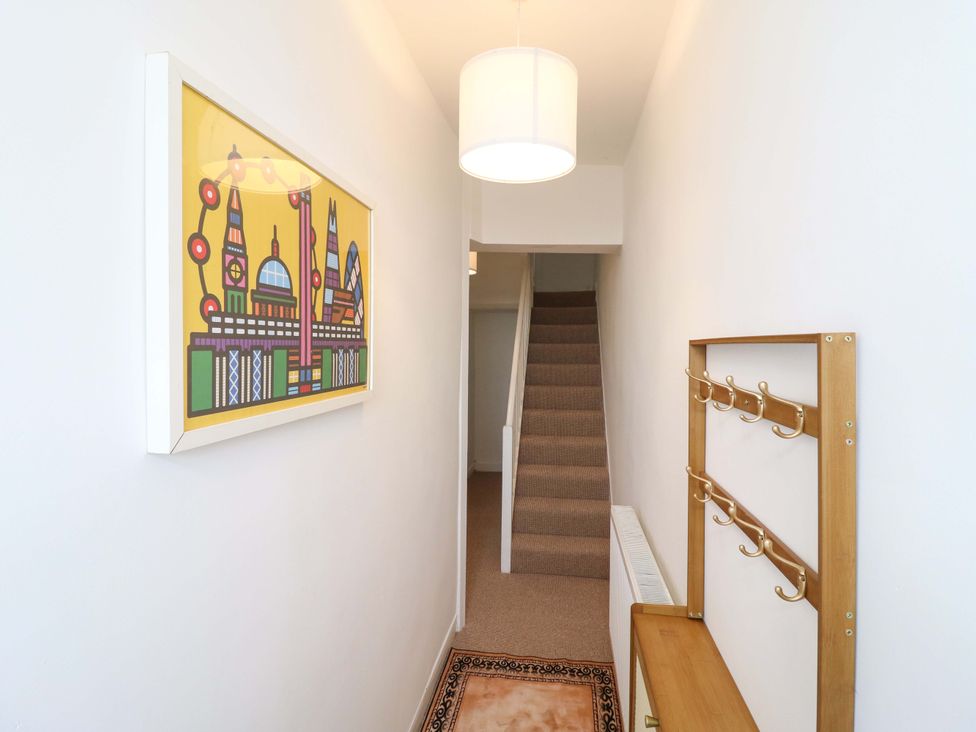 A hallway with a staircase and coat rack at 7 Athol Terrace