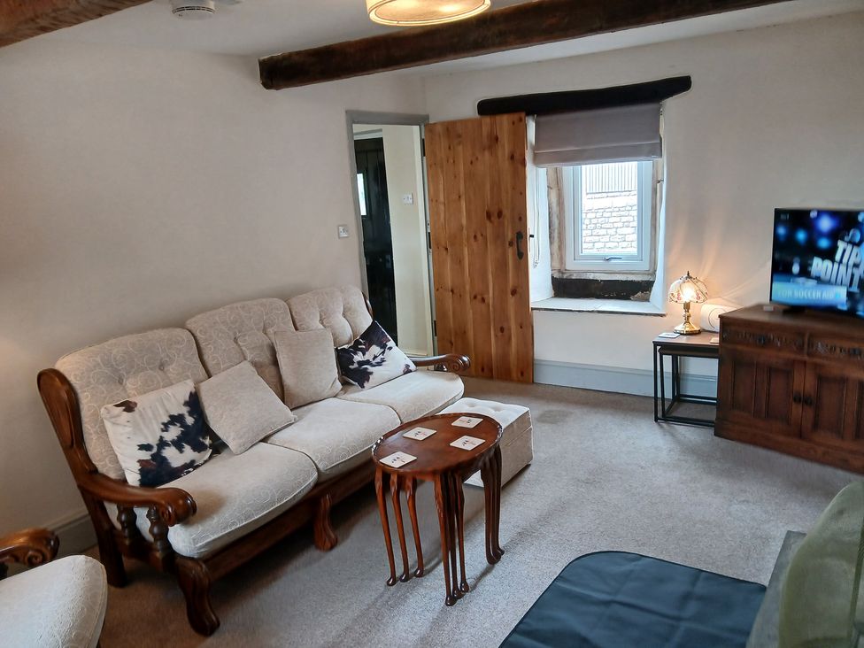 A living room with a sofa and a television at 4 Oak Cottages in Bentham, Yorkshire