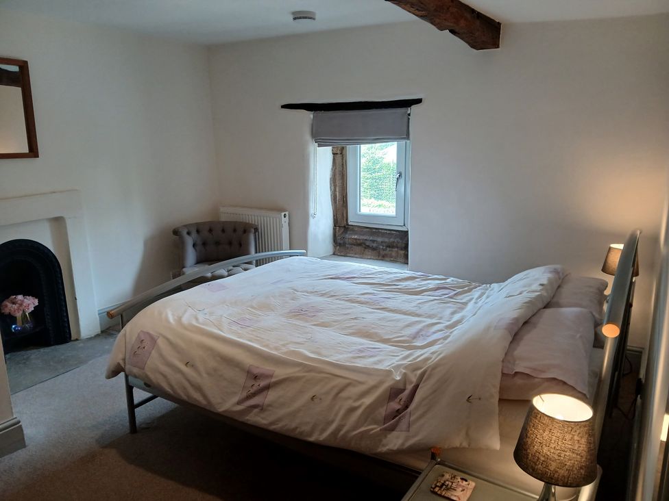 A bedroom with a bed and armchair at 4 Oak Cottages in Bentham, Yorkshire