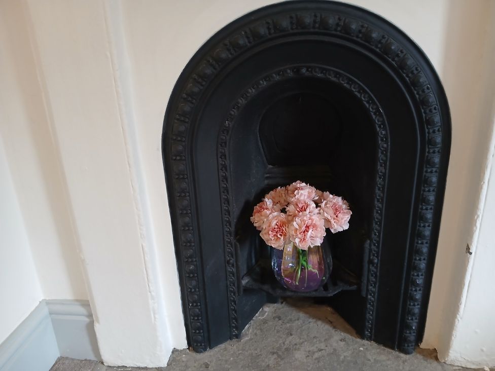 A fireplace with flowers in a vase at 4 Oak Cottages Bentham, Yorkshire