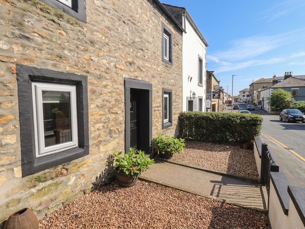 An outdoor area with a stone wall and gravel path at 4 Oak Cottages in Bentham, Yorkshire