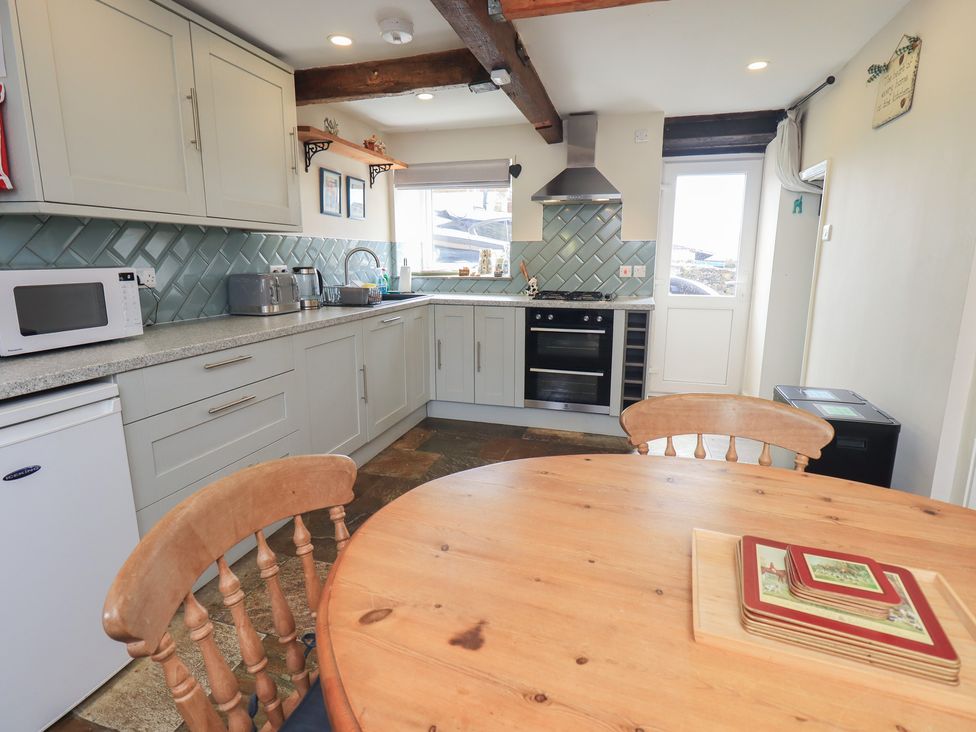 A kitchen with appliances and a dining table at 4 Oak Cottages in Bentham, Yorkshire