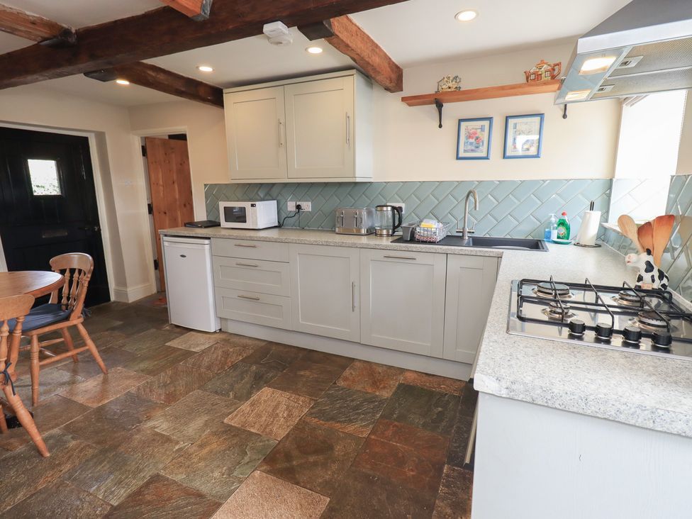 A kitchen with cabinets and a table at 4 Oak Cottages in Bentham, Yorkshire