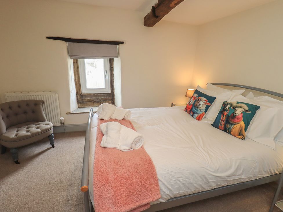 A bedroom with a bed and a chair at 4 Oak Cottages in Bentham, Yorkshire