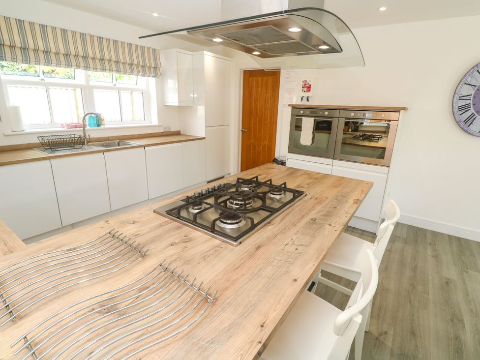 A kitchen with a gas stove and wooden table at Rosevale Villa in St Ives