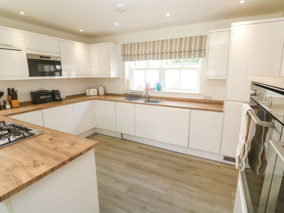 A kitchen with modern appliances and wooden countertop at Rosevale Villa, St Ives