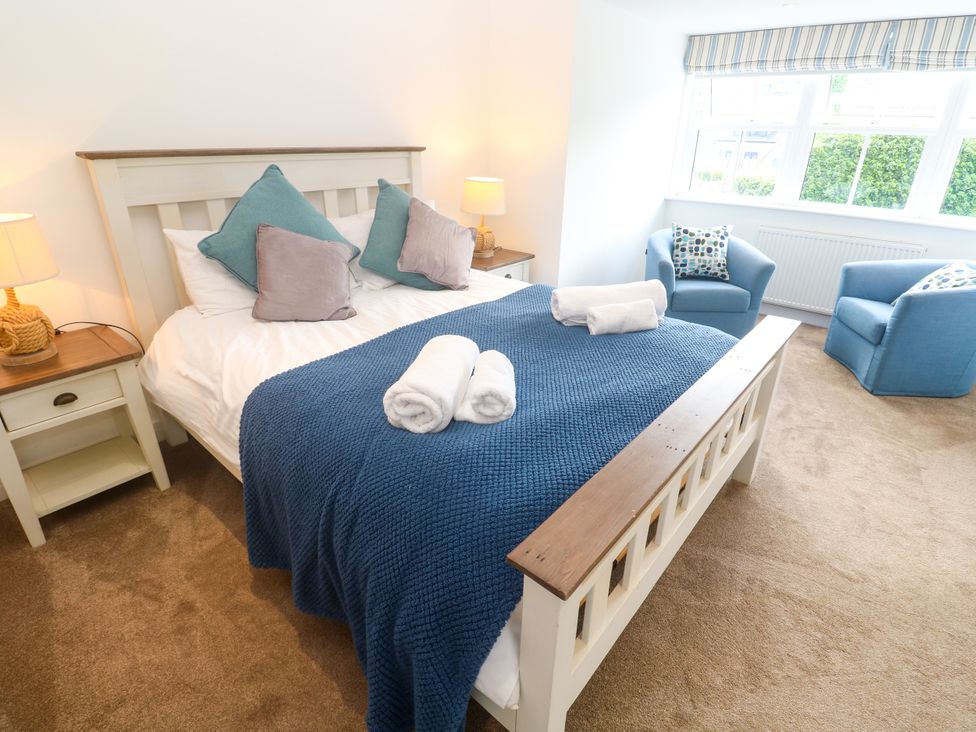 A bedroom with a bed and chairs at Rosevale Villa in St Ives