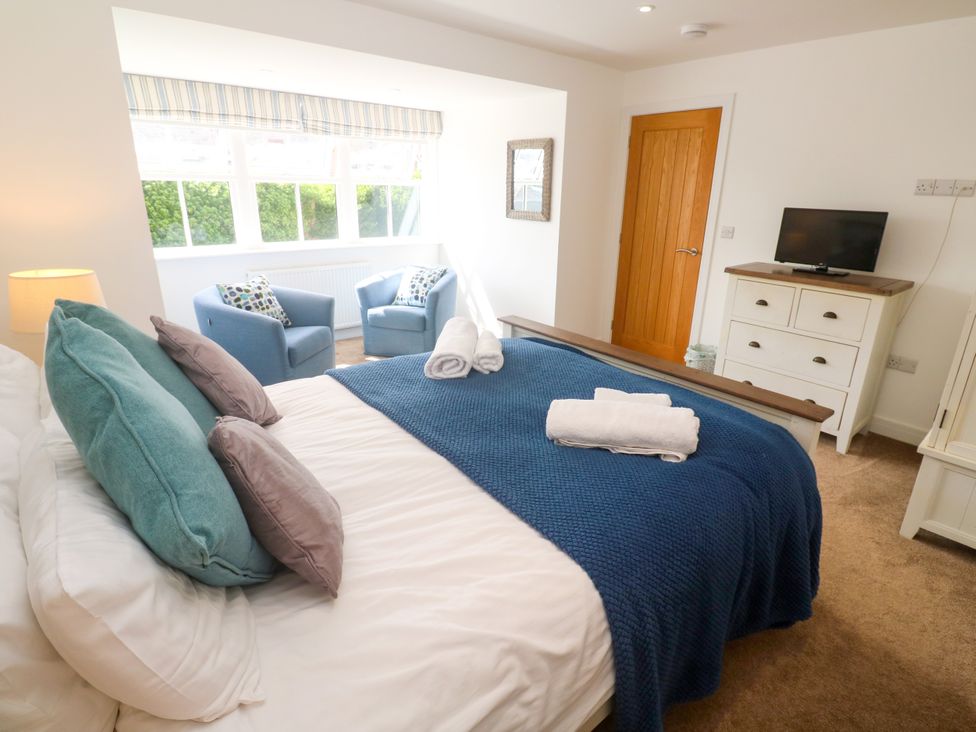 A bedroom with a bed and armchairs at Rosevale Villa St Ives