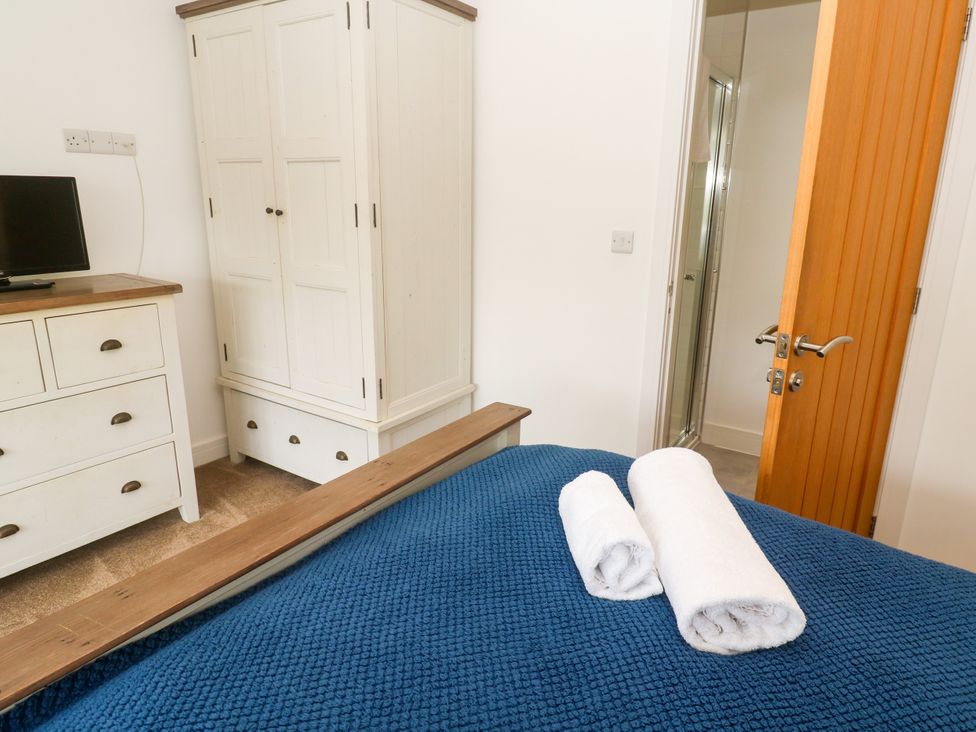 A bedroom with a bed towels and wardrobe at Rosevale Villa St Ives