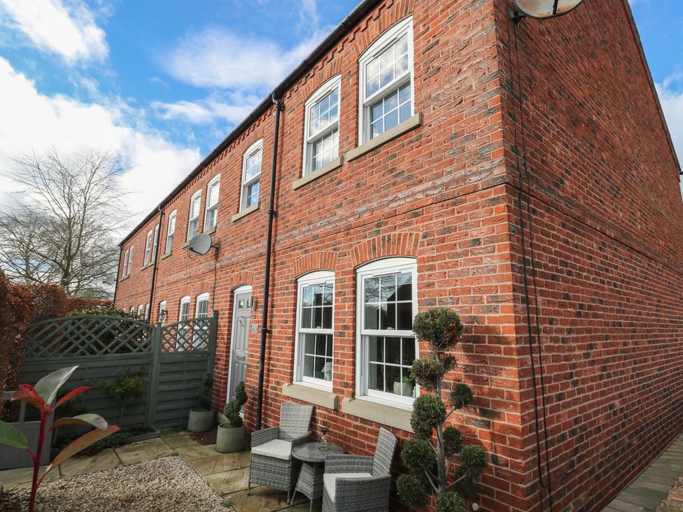 An outdoor seating area with brick wall and plants at Olive Tree Cottage in York