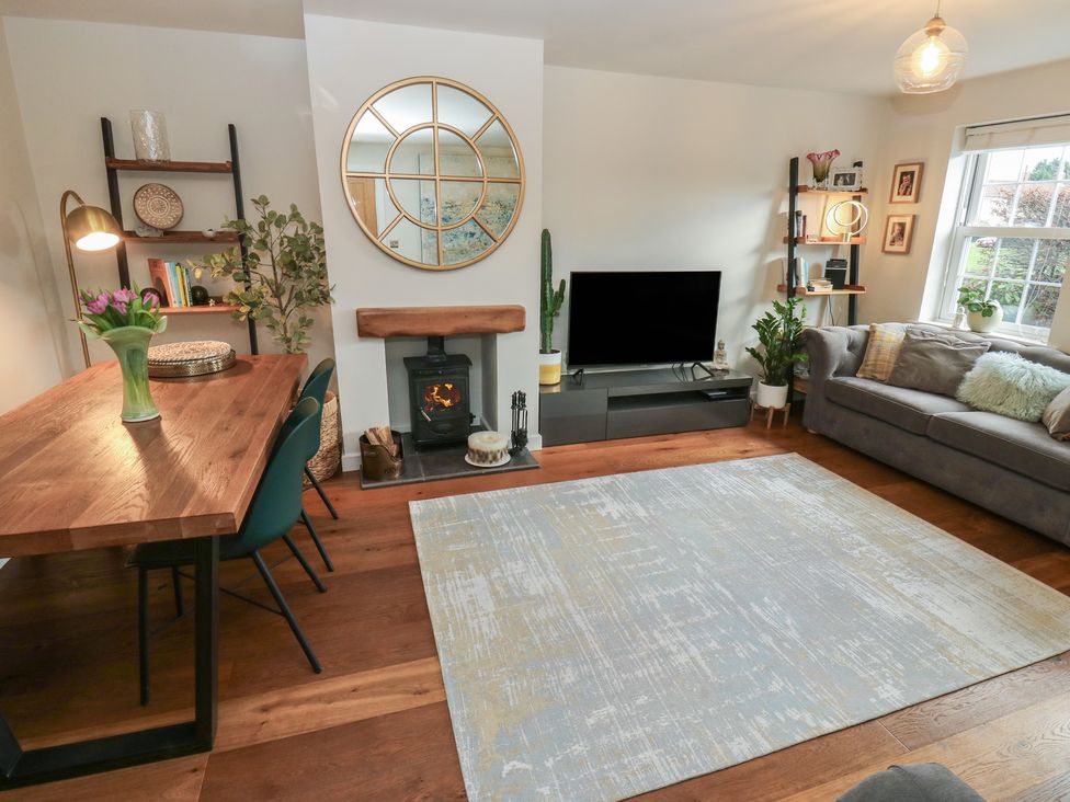 A living room with a dining table and a television at Olive Tree Cottage in York