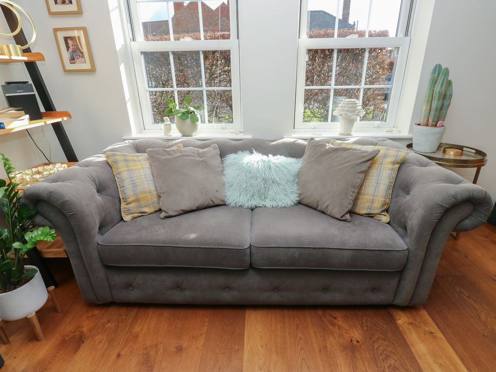 A living room with a grey sofa and decorative pillows at Olive Tree Cottage in York
