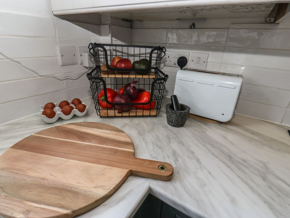 A kitchen with a chopping board and a basket of fruits at Olive Tree Cottage in York
