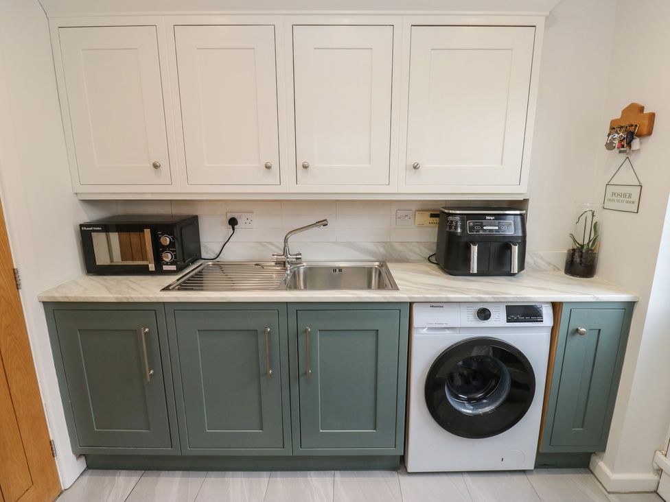 A kitchen with a sink, microwave, and washing machine at Olive Tree Cottage, York
