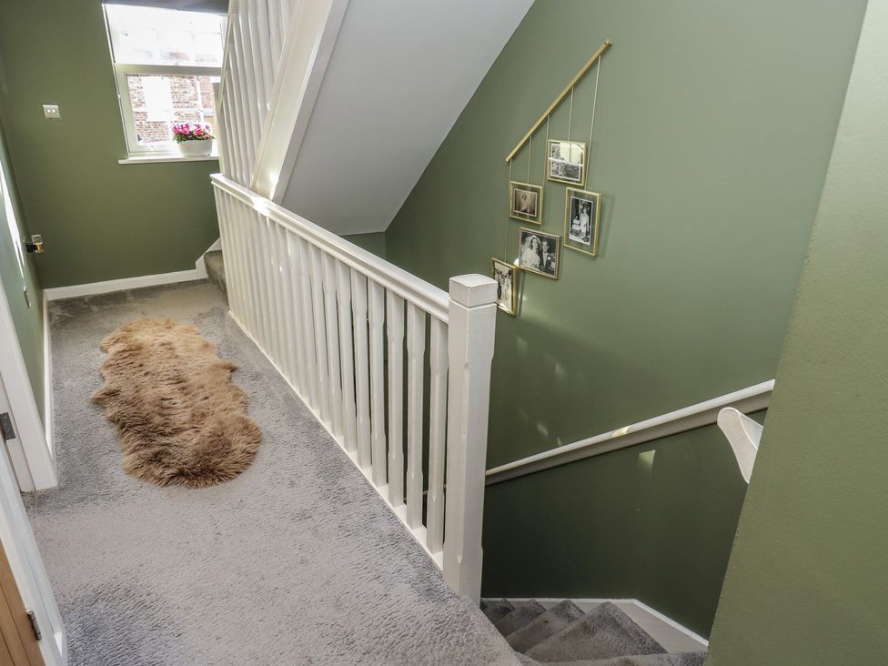 A staircase in a hallway with photographs on the wall at Olive Tree Cottage in York