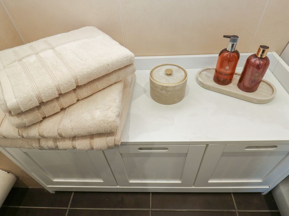 A bathroom countertop with towels and toiletries at Olive Tree Cottage York