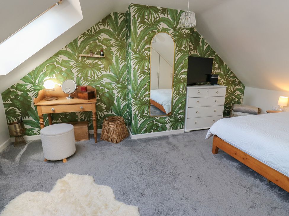 A bedroom with a bed, television, and dressing table at Olive Tree Cottage in York