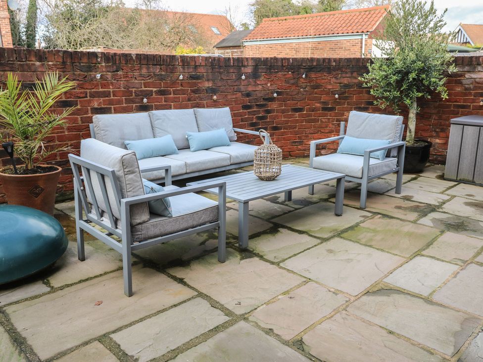 A garden with a sofa and armchairs around a coffee table at Olive Tree Cottage in York