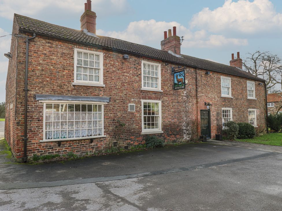 A brick building with windows and a sign at Olive Tree Cottage in York
