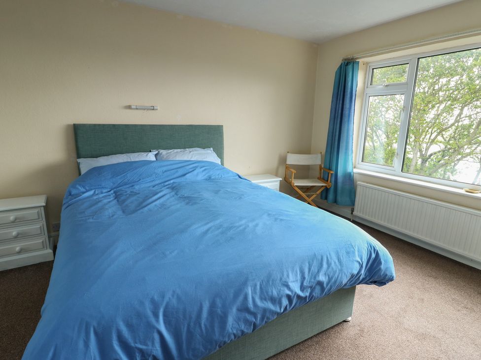 A bedroom with a bed and a chair at Bryn Y Felin Y Felinheli
