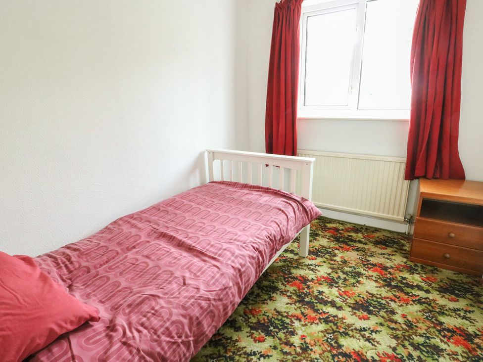 A bedroom with a bed, window, and bedside table at Bryn Y Felin Y Felinheli