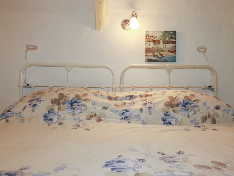 A bed with floral bedding and wall light at Plenteth in Truro