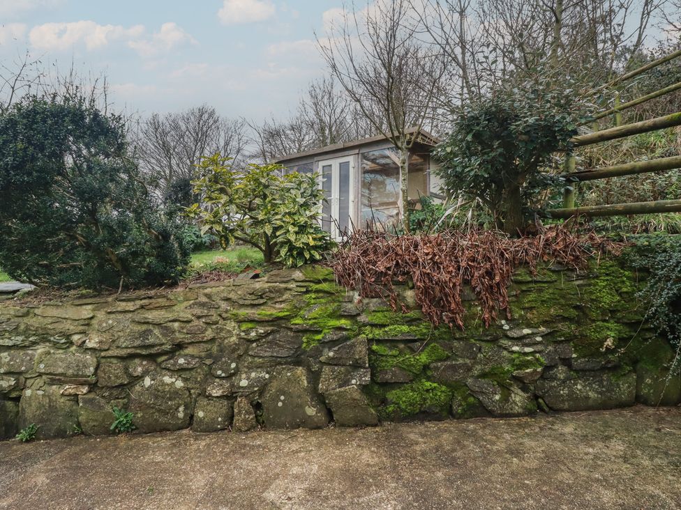 A garden with a stone wall and a shed at Plenteth in Truro