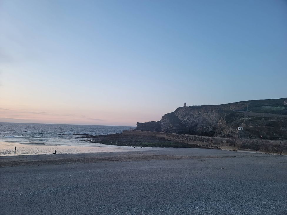 A beach with a person and dog at the shoreline at 16 Forth An Nance Portreath