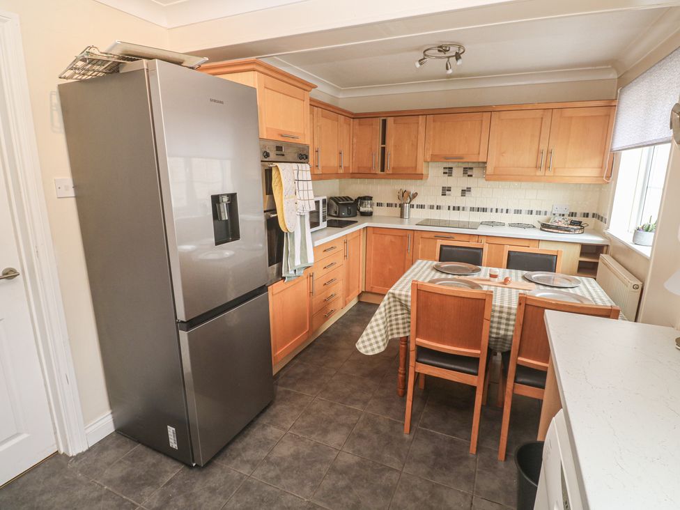 A kitchen with a refrigerator, stove, and dining table at 16 Forth An Nance Portreath