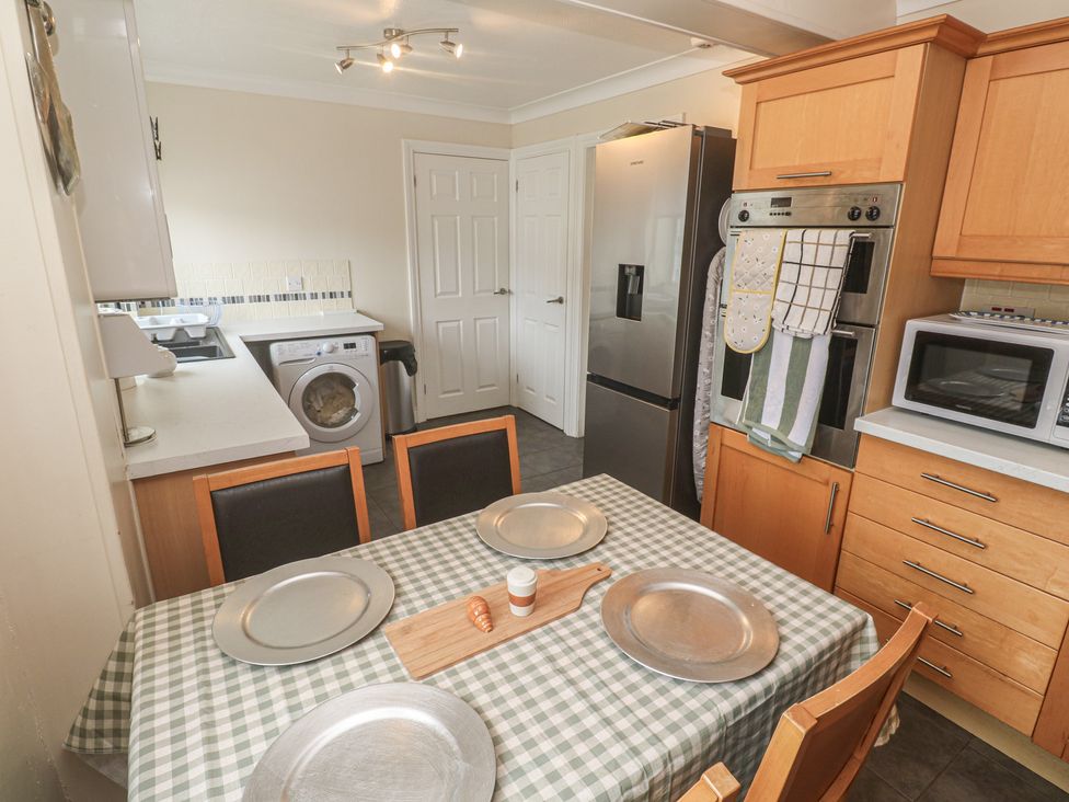A kitchen with appliances and a dining table at 16 Forth An Nance in Portreath