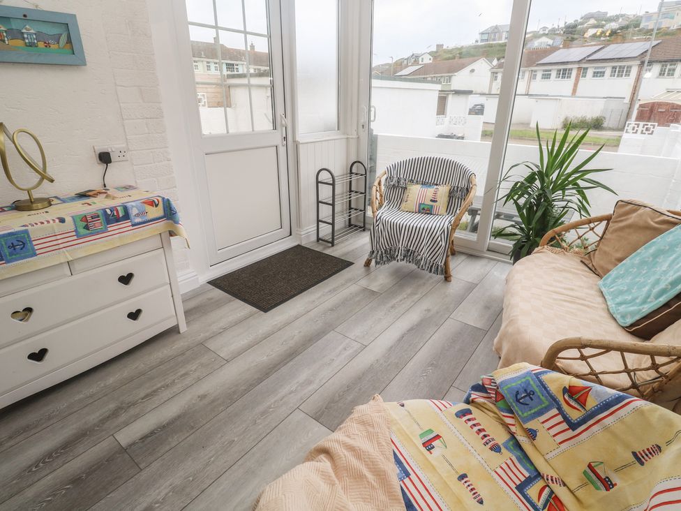 A conservatory with a sofa and chair at 16 Forth An Nance in Portreath