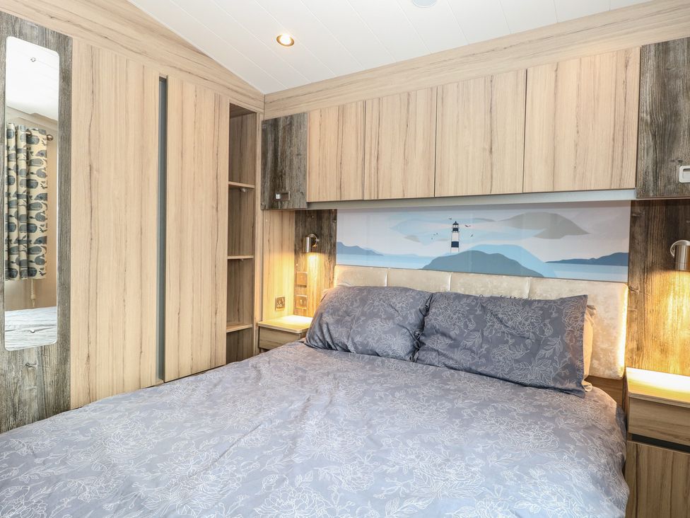 A bedroom with a bed and shelves at Caravan in Great Yarmouth