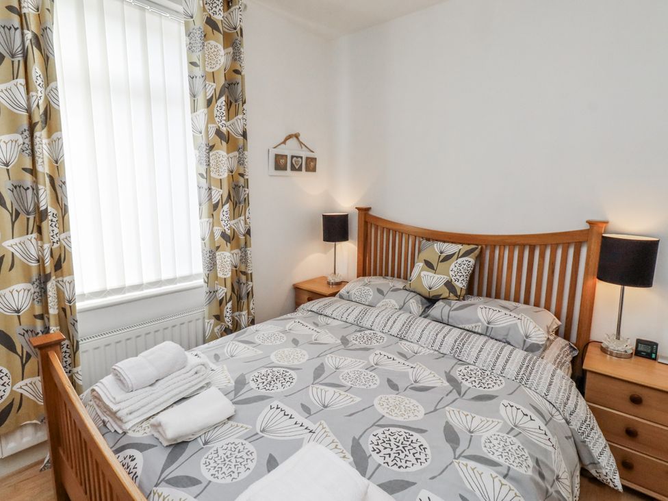 A bedroom with a wooden bed and nightstands at 55 Meldon terrace Newbiggin-by-the-Sea