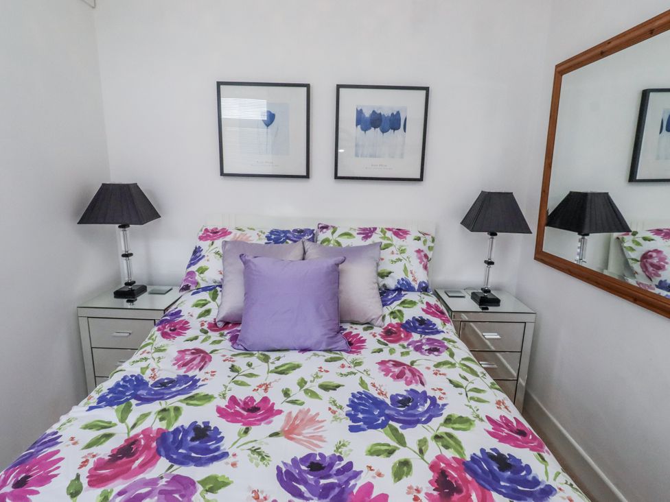A bedroom with a floral bedding and two lamps at 55 Meldon terrace in Newbiggin-by-the-Sea