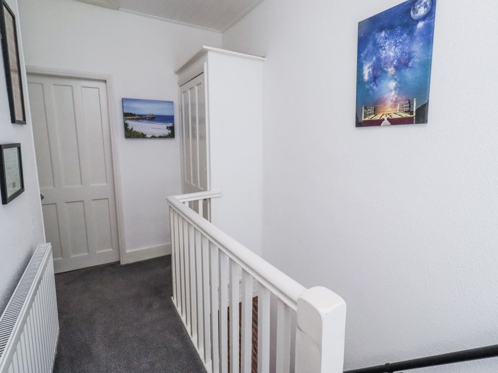 A hallway with a door and wall art at 55 Meldon terrace in Newbiggin-by-the-Sea