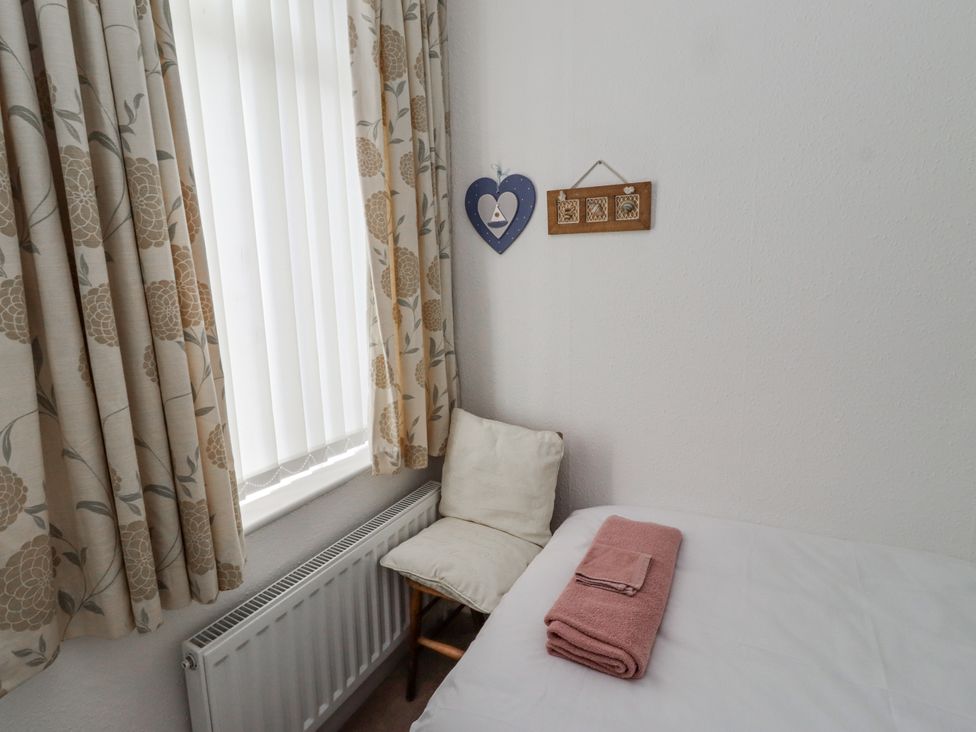 A bedroom with a chair and a towel on the bed at 55 Meldon terrace in Newbiggin-by-the-Sea
