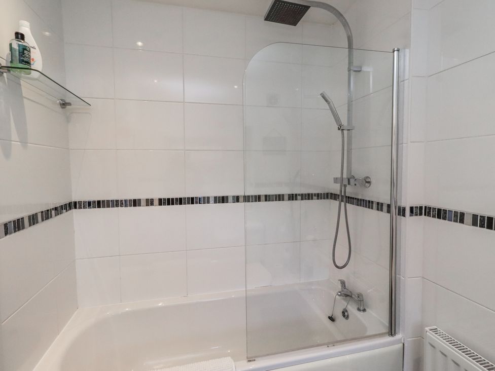 A bathroom featuring a bathtub with a shower and shelf at 55 Meldon terrace in Newbiggin-by-the-Sea