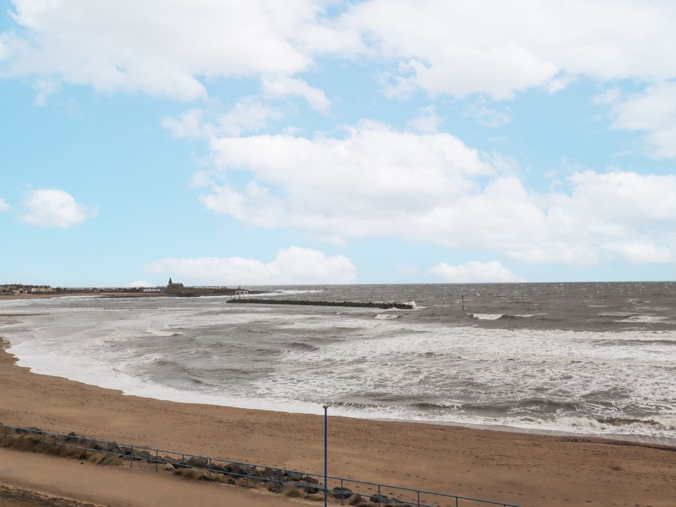 A beach with waves and a pier at 55 Meldon terrace in Newbiggin-by-the-Sea
