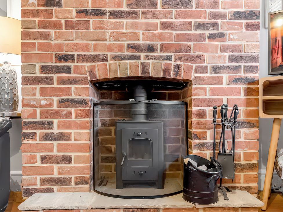 A fireplace with wood stove and tools at Bay Tree Cottage in Heacham