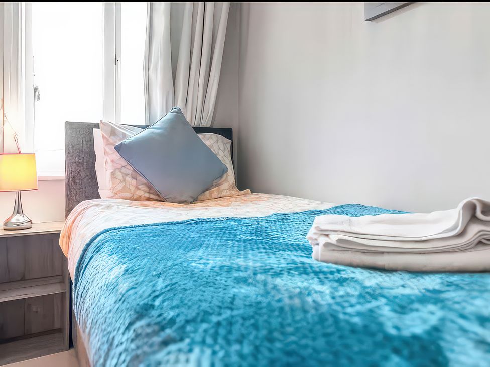A bedroom with a bed and lamp at Bay Tree Cottage in Heacham