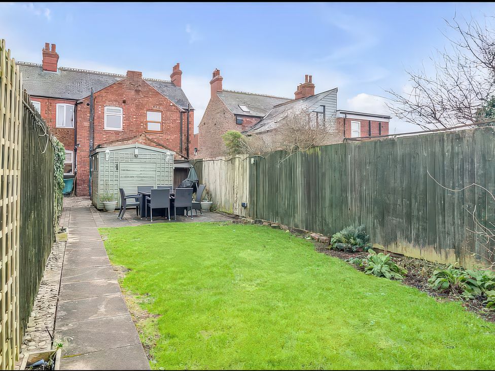 A garden with grass and a patio area at Bay Tree Cottage in Heacham
