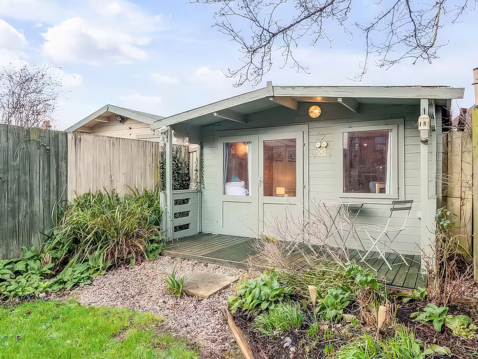 A garden shed with doors and windows at Bay Tree Cottage in Heacham