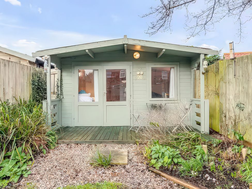 A cabin with a deck and garden at Bay Tree Cottage in Heacham