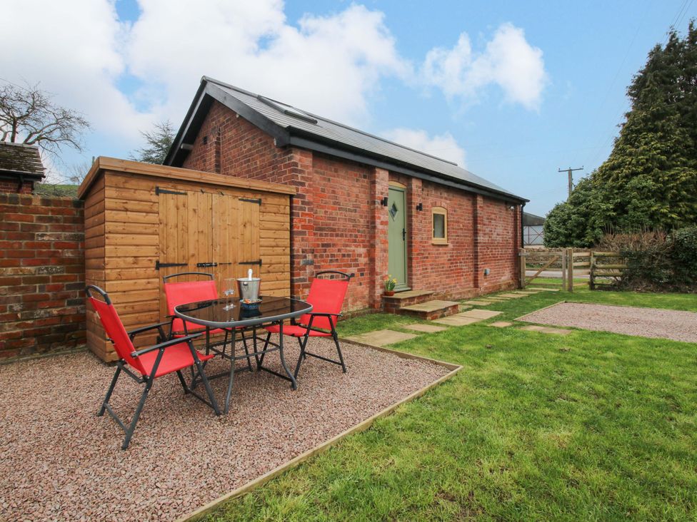 An outdoor area with a table and chairs next to a shed at The Blacksmiths Shop