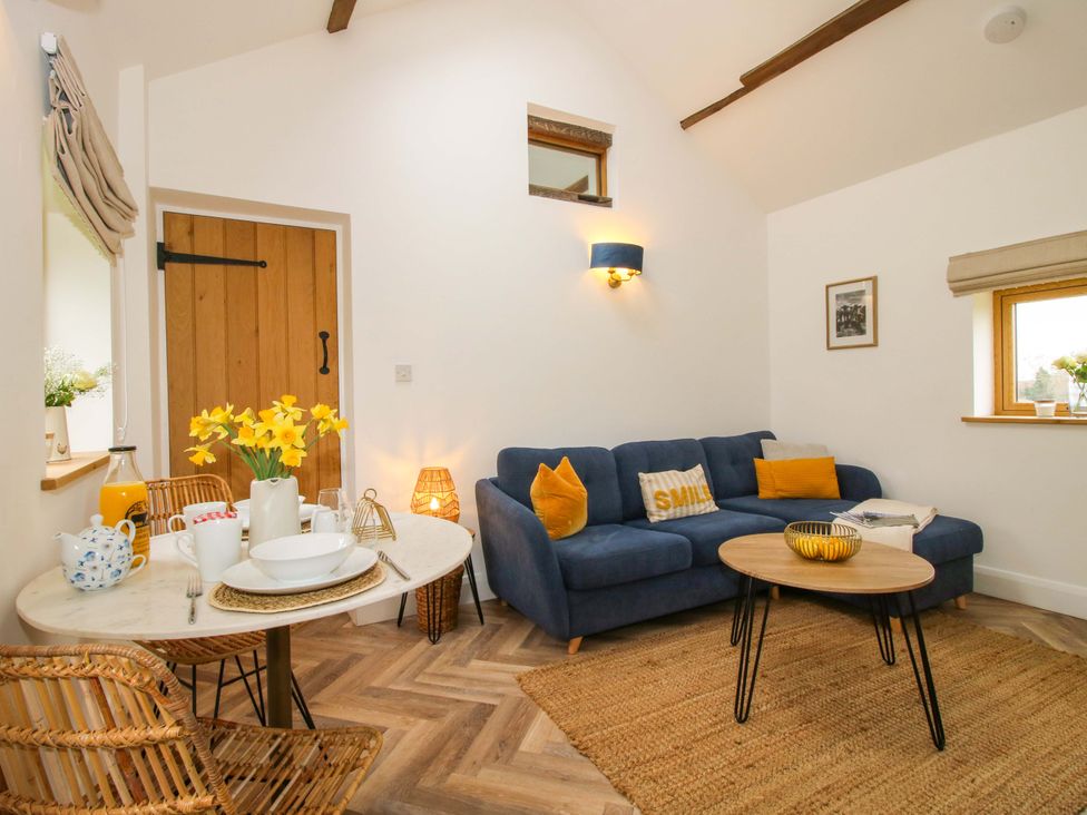A living room with a sofa, coffee table, and dining table at The Blacksmiths Shop in 