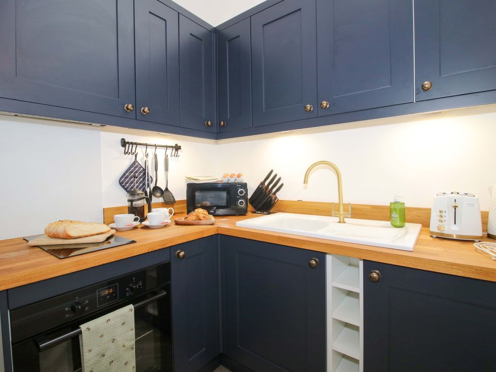 A kitchen with dark cabinets and wooden counter at The Blacksmiths Shop in 