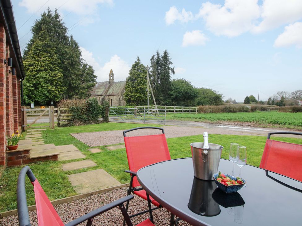 A patio with a table and chairs overlooking a field at The Blacksmiths Shop