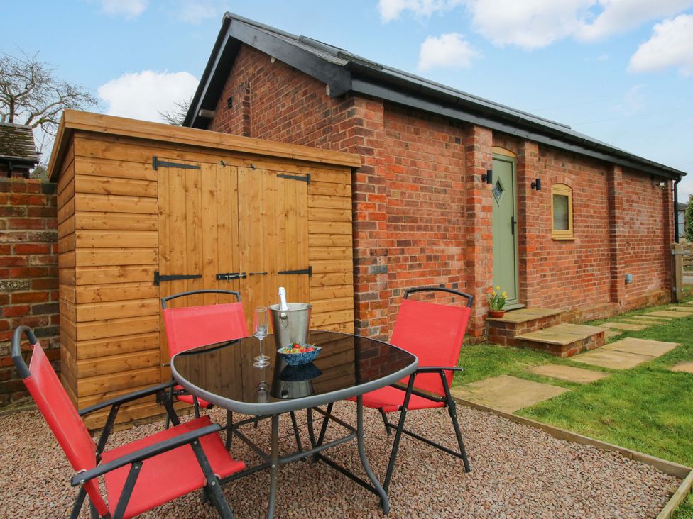 An outdoor area with a table and chairs near a storage shed at The Blacksmiths Shop