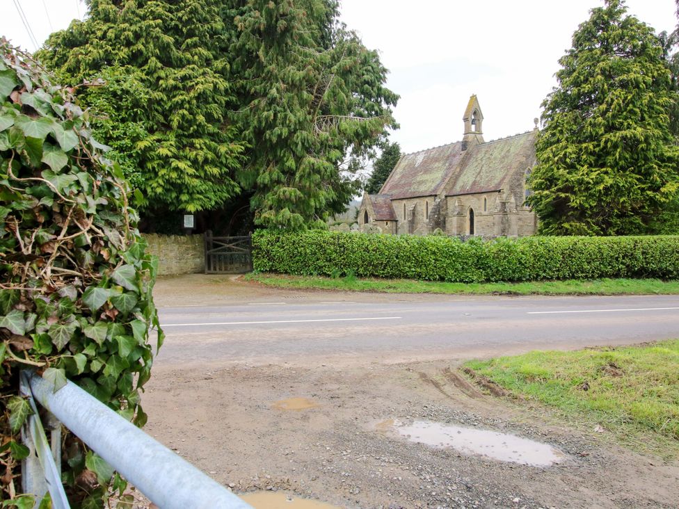 A church surrounded by trees and a hedge next to a road at The Blacksmiths Shop in 