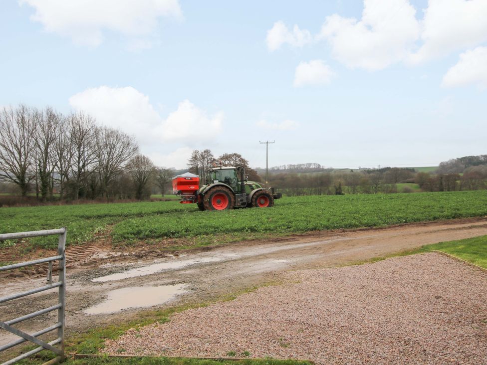 A tractor working in a field with trees in the background at The Blacksmiths Shop 